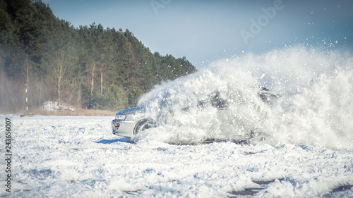 Extreme driving, the car is moving rapidly over the smooth snow and creates a spray of snow.