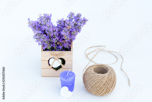 Fototapeta Naklejka Na Ścianę i Meble -  Fresh lavender in a small basket with heart, hemp ball, purple candle and white heart on white wooden background