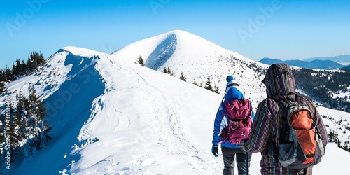 Tourists in winter top mountains panorama, Women go on snowy mountain peak, Symbol winter hiker experience