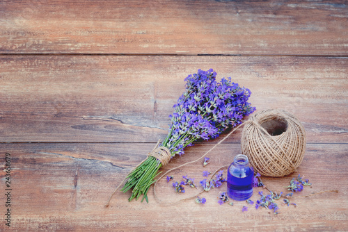 Fototapeta Naklejka Na Ścianę i Meble -  Fresh bouquet of lavender, hemp ball and lavender essential oil on brown wooden background.