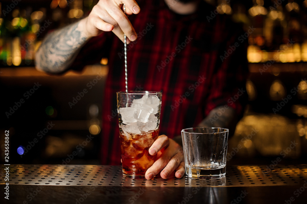 Bartender stirring a Foreign Legion cocktail with the spoon
