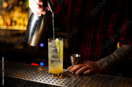 Foto Bartender pouring a soda to a Lynchburg lemonade cocktail from the siphon