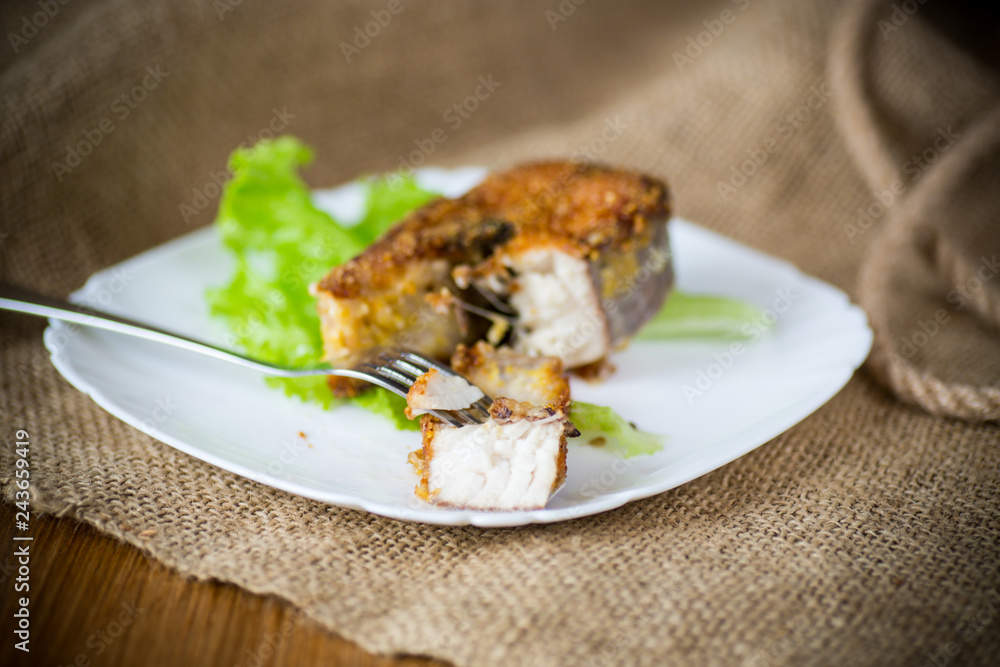 piece of fried pike fish in a plate on a wooden