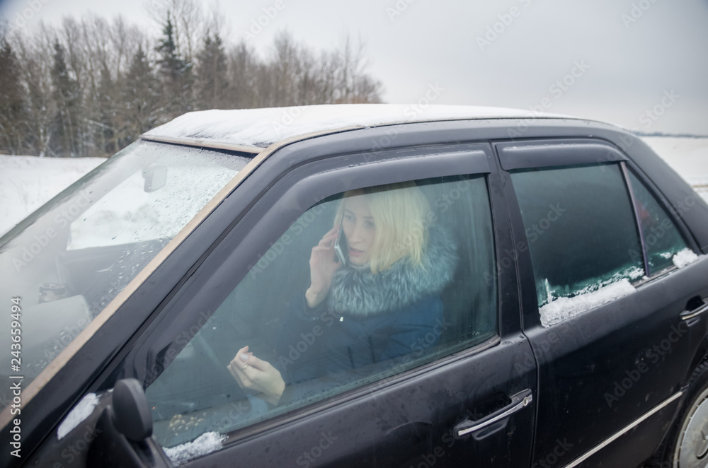 Blonde girl talking on the phone while driving a car