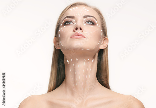 Close-up portrait of young, beautiful and healthy woman with arrows on her face. The spa, surgery, face lifting and skin care concept photo