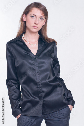 Beautiful young woman in black shirt and trousers on bright background. Fashion studio shoot