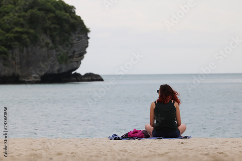 Tourist girl reading a book relaxing on a tropical beach in the evening. © THANAGON
