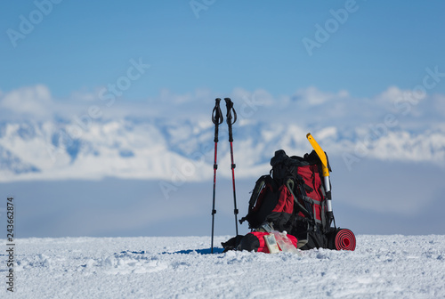 Backpack and hiking poles of a winter hiker in the snow.