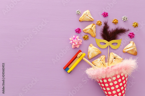 Purim celebration concept (jewish carnival holiday) over wooden purple background. © tomertu