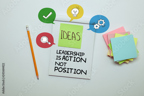 elevated view of paper sticker with word ideas in notebook with "Leadership is action, not position" lettering and icons
