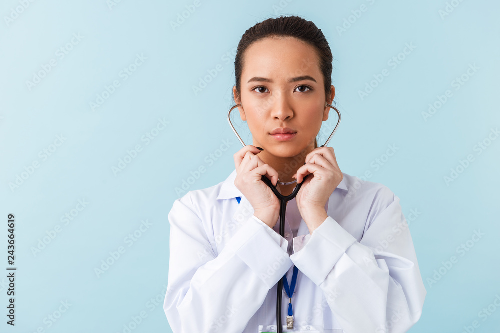 Woman doctor posing isolated over blue wall background with stethoscope.