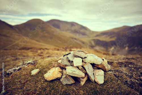 A cairn, pile of stones marking a mountain top, waypoint in the English Lake District. Summit of Outerside with Sail and Crag Hill in the distance. photo