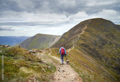 A hiker decending Sail and walking along The Scar towards Crag Hill in the Derwent Fells in the English Lake District.