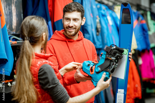Fototapeta Naklejka Na Ścianę i Meble -  Man and woman choosing sports equipment looking on the ski and boots for skiing in the shop