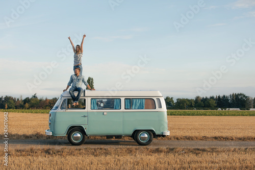 Happy couple on roof of a camper van in rural landscape photo