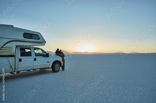 Bolivia, Salar de Uyuni, mother and son at camper on salt lake at sunset photo