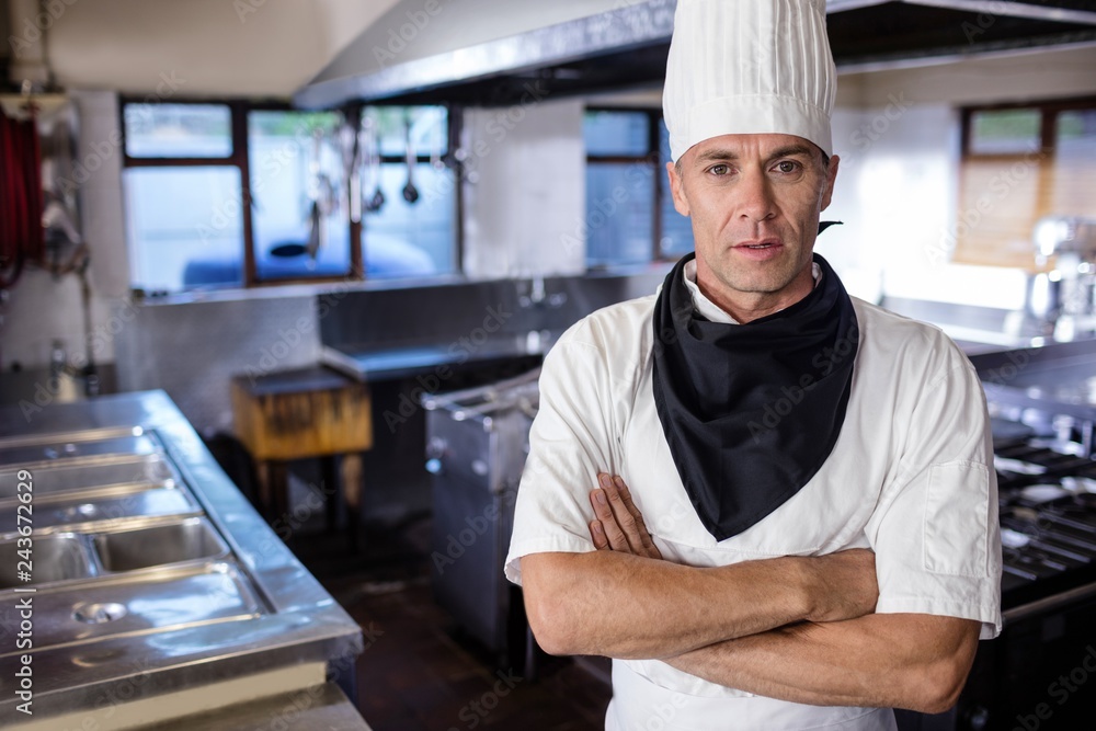 Male chef standing with arms crossed in kitchen Male chef standing with arms crossed in kitchen
