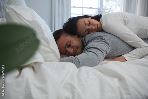 Couple sleeping on bed in bedroom