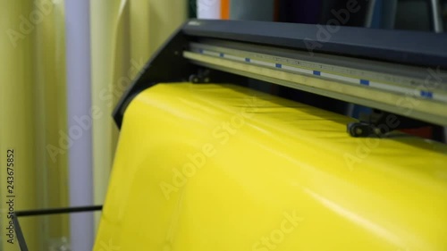 closeup long yellow vinyl rolling sheet moves through modern large format cutting appliance