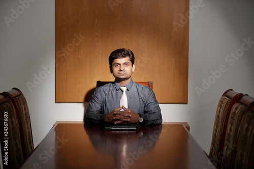 Confident Indina company CEO sitting at the head of table in meeting room photo