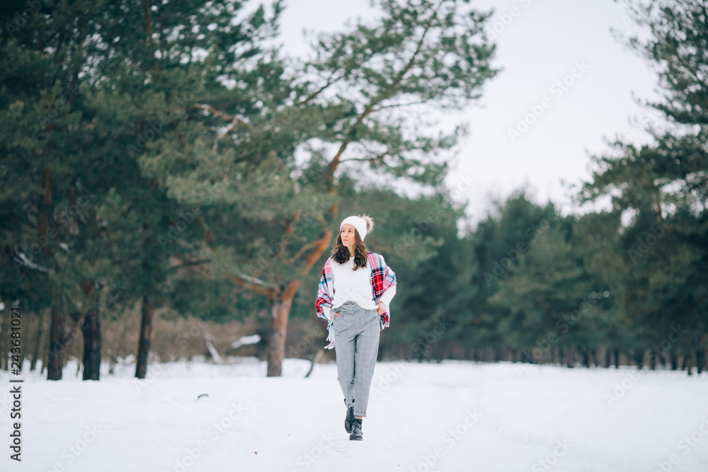 A young woman walks through the winter forest.