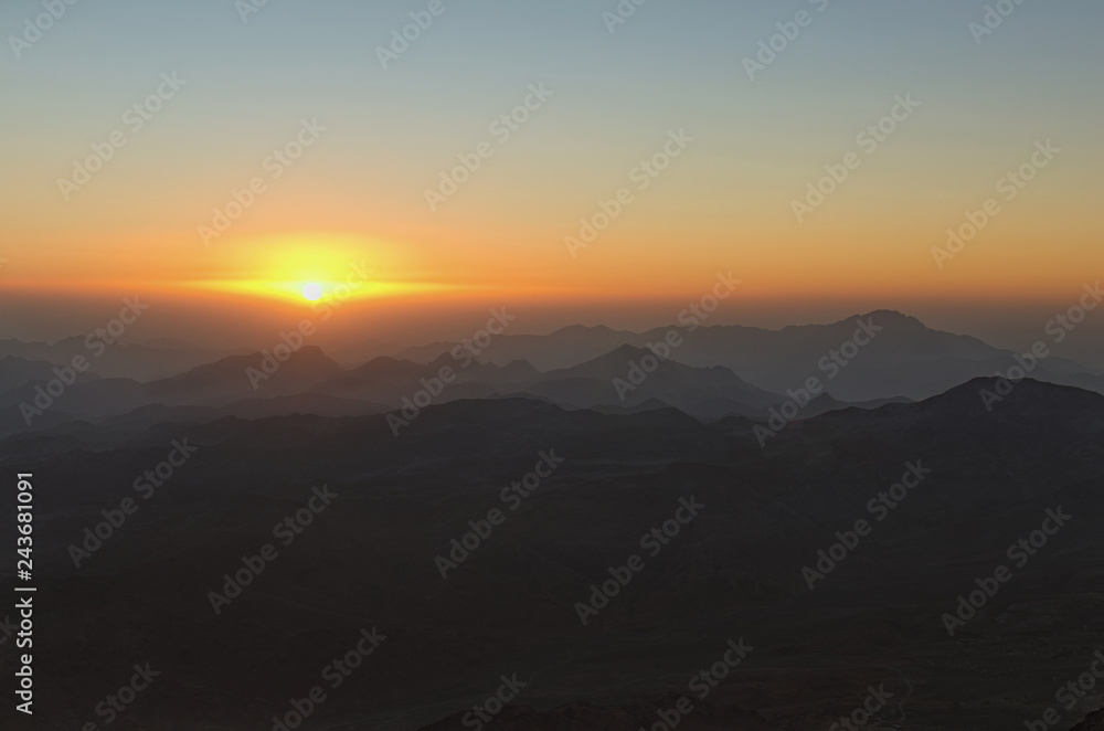 Amazing golden sunrise in the mountains. White sun disk on the mountains. View from Mount Sinai (Mount Horeb, Gabal Musa, Moses Mount). Sinai Peninsula of Egypt