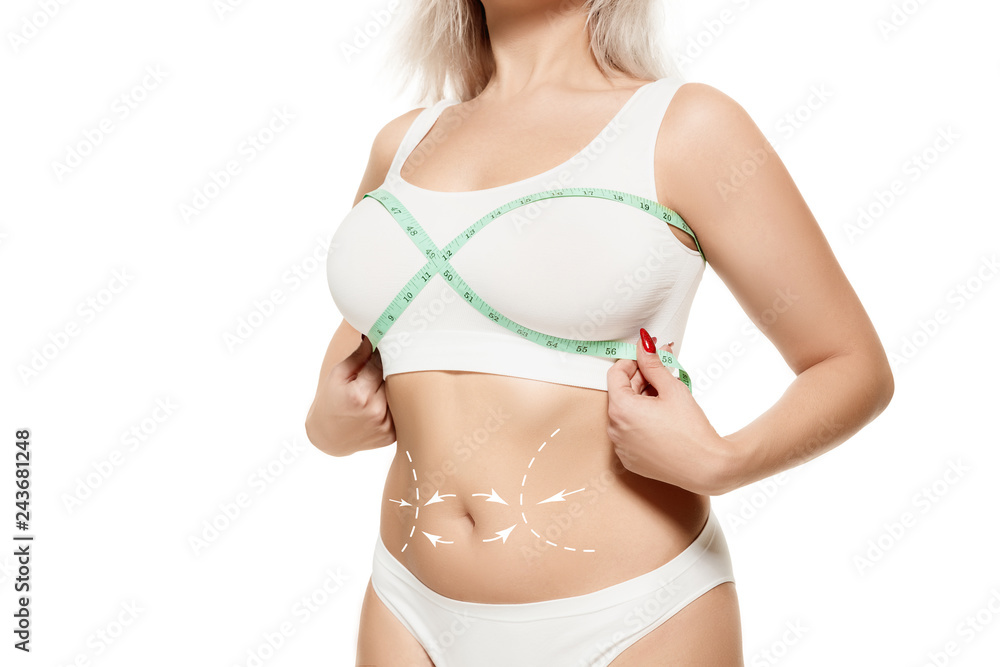 Beauty body care. Woman holding the meter with hands and measuring waist. Fat lose, liposuction and cellulite removal concept. Marks on the women's body before plastic surgery.