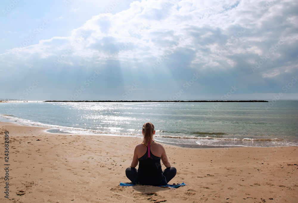 girl meditating on the beach in the sun