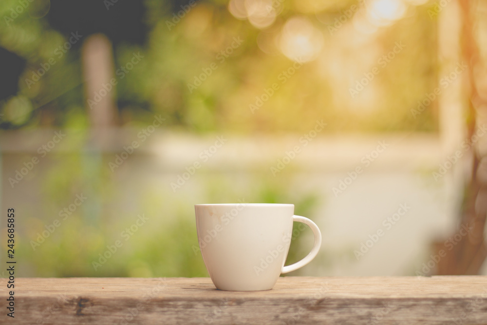 Cup of hot coffee on table in morning sunlight.