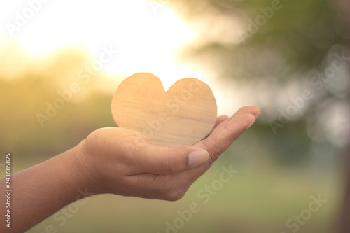 Wood heart in hand on green background.Love valentine concept.