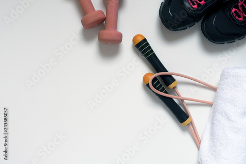 jump rope, black sneakers, dumbbells, white bath towel, pink close-up on a white background, there is a place for an inscription photo