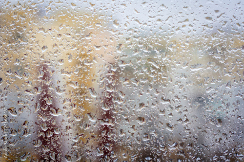 Raindrops on glass, window background view of buildings out of focus. photo