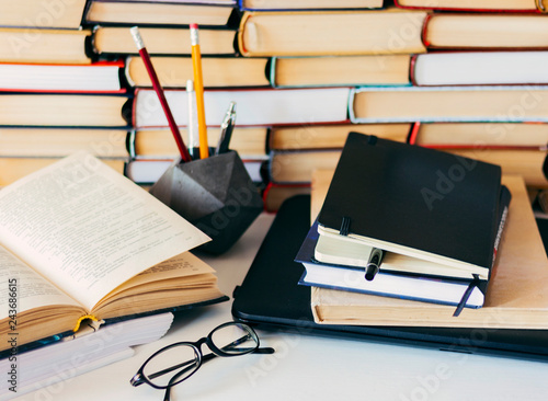 Stack of books, notebook, laptop, glasses in office background for education learning concept. photo