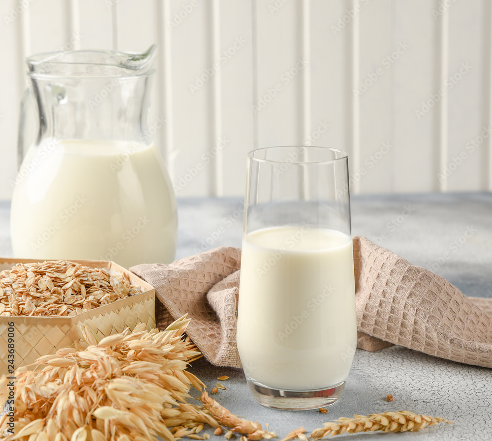 The concept of a vegetarian diet. Oat milk in the glass with jug of oat