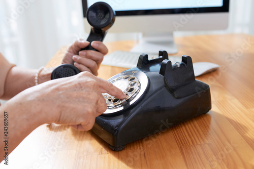Tablou pe pânză Aged woman using old phone when dialing telephone number