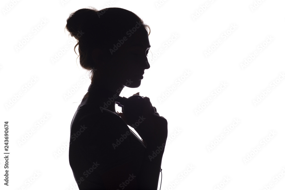 Silhouette of a girl with with headphones around neck, a young woman listening to music on a white isolated background, concept of hobby and relaxation