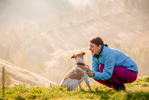 woman playing with her dog in beautiful mountain scenery in spring