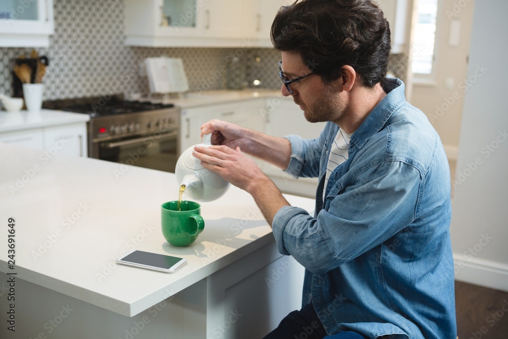Man pouring lemon tea into mug at home Man pouring lemon tea into mug at home