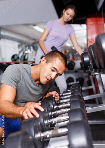 Cheerful man and girl choosing dumbbells