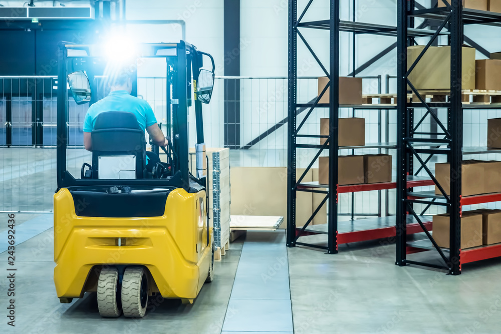 Warehouse equipment. Storage. The person works on a loader. Metal racks. Carton boxes. Forklift truck A man with a forklift loads boxes.