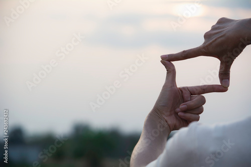 Hands making frame with sunset. Close up of woman hands making frame gesture.