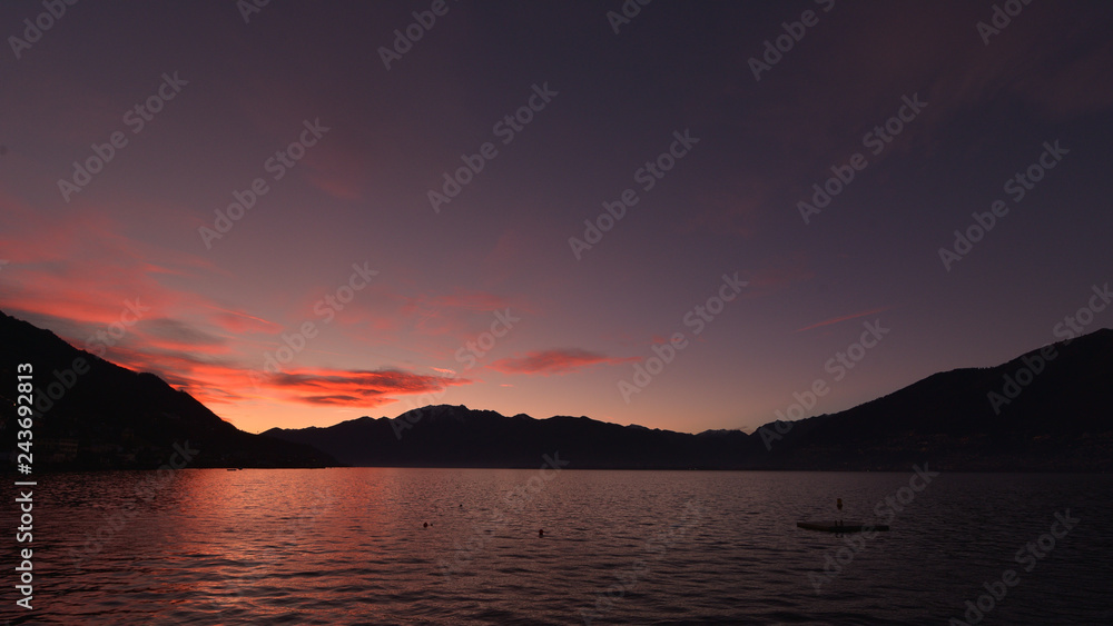 Tramonto sul lago, con nuvole rosse e rosa