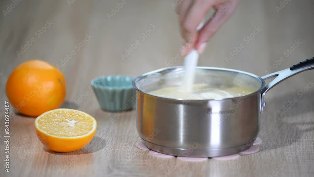 Female hand stir custard in the saucepan. Female hand stir custard in the saucepan.