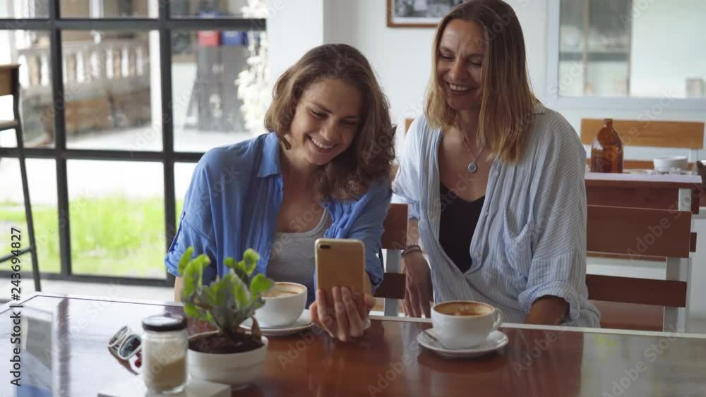 Two woman sharing coffee using smartphone in cafe Two woman sharing coffee using smartphone in cafe