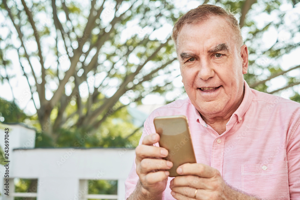 Portrait of happy elderly man using application on smartphone