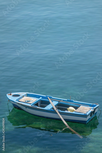 Small white blue boat with paddles anchored on the shore