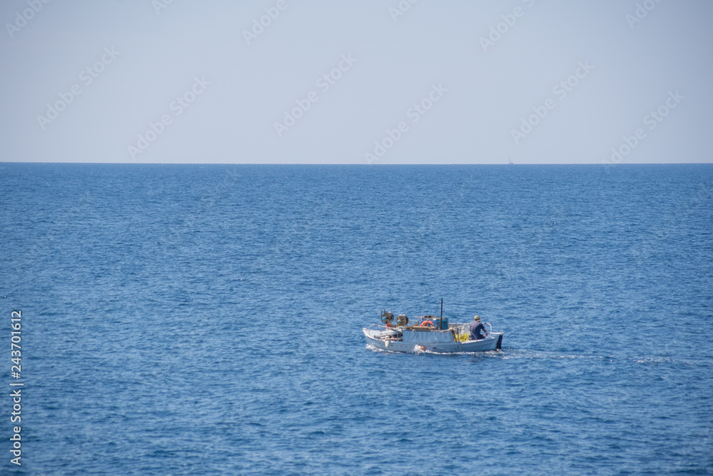 Small white motorized boat with one man sails in the open sea