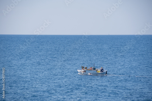Small white motorized boat with one man sails in the open sea © Zoran