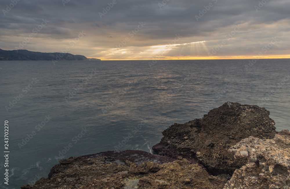 Nerja, Malaga, Andalusi, Spain - November 25, 2018: Long exposure on the coast with a rocks in the foreground under a stormy sky
