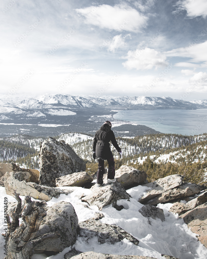 Snowboarder/Hiker at Summit with View of Lake Tahoe and Sierra Nevada Mountains on a Clear Cloudy Day